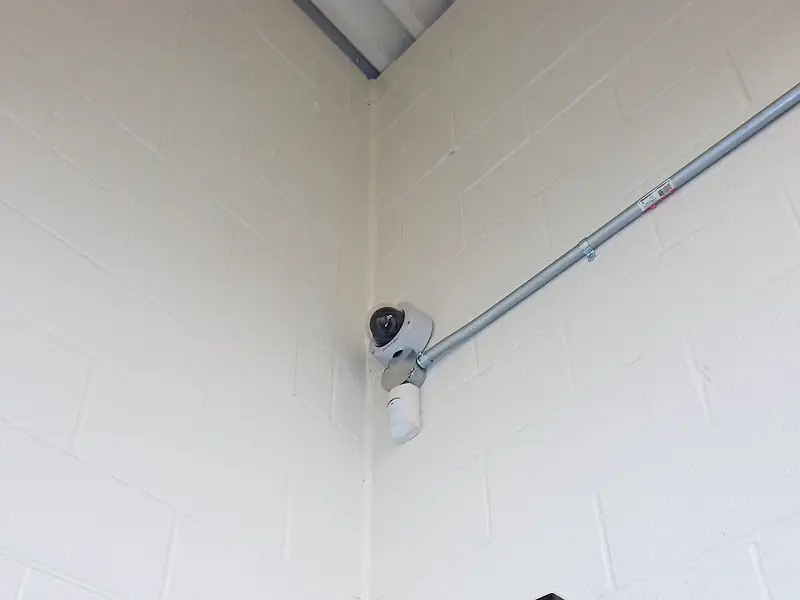 Camera in the corner of a block wall, fed by surface conduit.