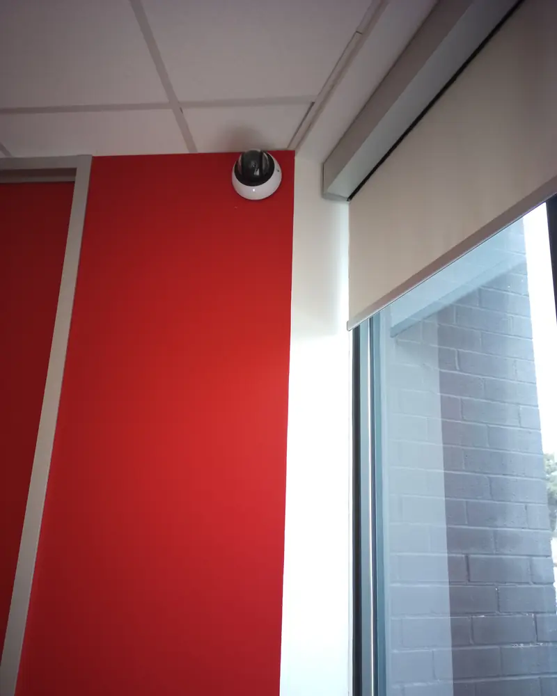 Dome camera at the ceiling line of a red interior wall.