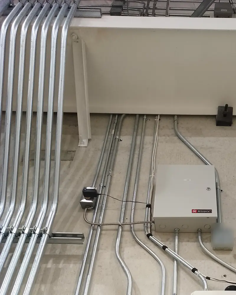 A bank of parallel conduits with matching offsets running down a concrete wall to enclosures.