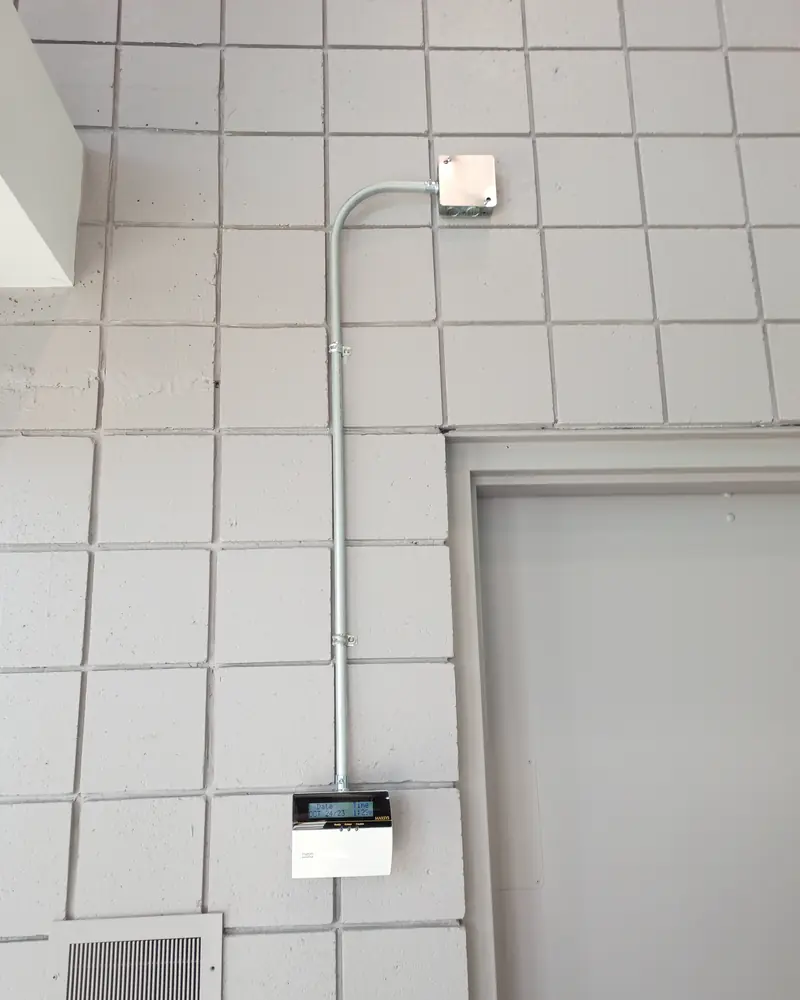 Surface conduit running down a block wall from a junction box to a keypad beside a door.