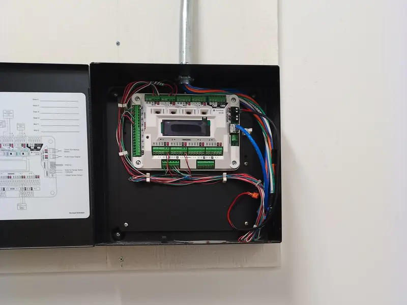 Compact door controller in a wall enclosure fed by conduit from above.