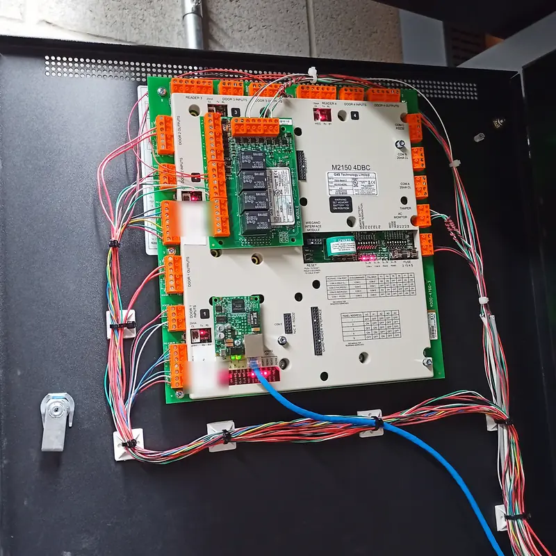 Single door controller in a black enclosure, its wiring tied to mounts around the board.