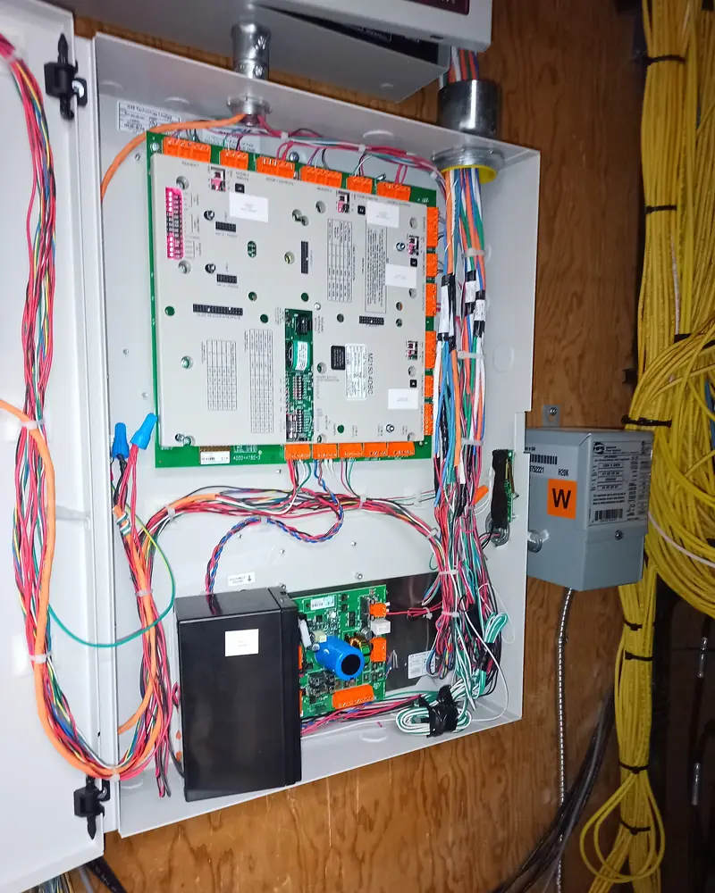 Door controller in an enclosure, its field wiring bundled and tied down one side.