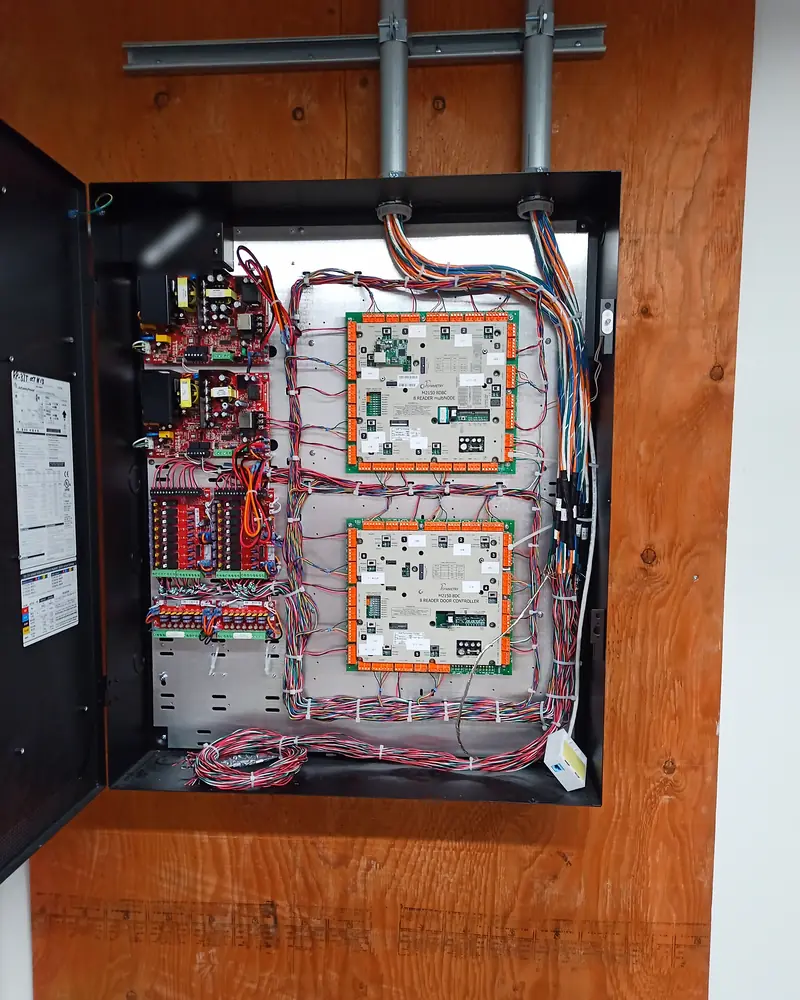 Enclosure on a plywood backboard with two door controllers, conduit entering from above.