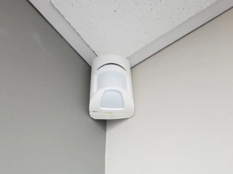 Motion detector mounted high in the corner of a room.