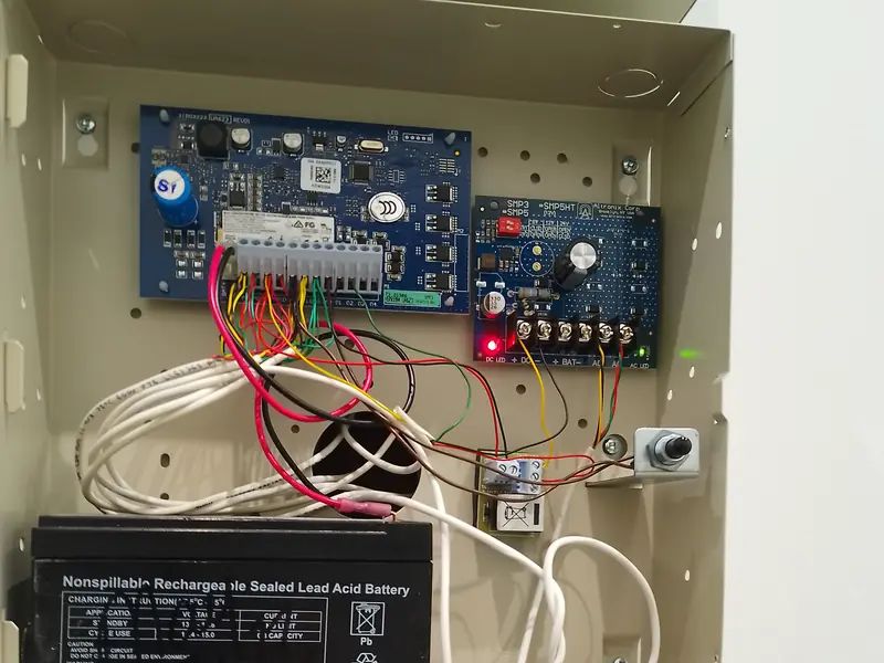 Alarm board and power supply in an open enclosure, conductors dressed to the terminals.