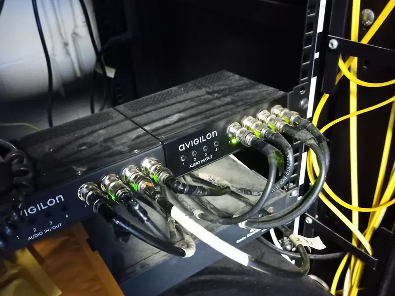 Video encoders in a rack beside yellow fibre patch cords.